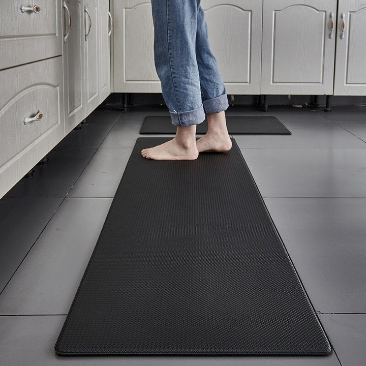 Anti-fatigue kitchen rug near stove. Waterproof PVC mat for cushioned comfort, anti-slip, and spill protection.