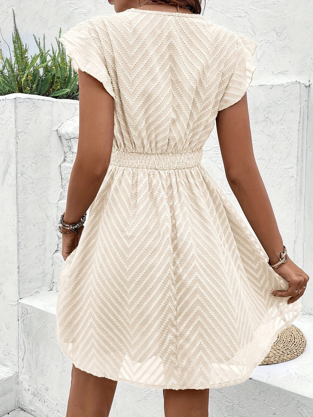Women's V-neck mini dress with elegant flutter sleeves. Flared and textured, a chic summer staple for women.