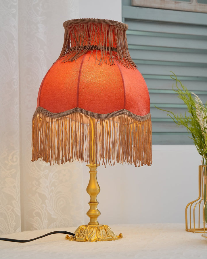 Bohemian red table lamp, Arina, featuring a sturdy brass base, provides accent lighting.