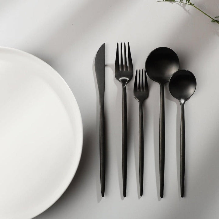 Elegant Aurora gold cutlery set on a white tablecloth, minimalist dining.