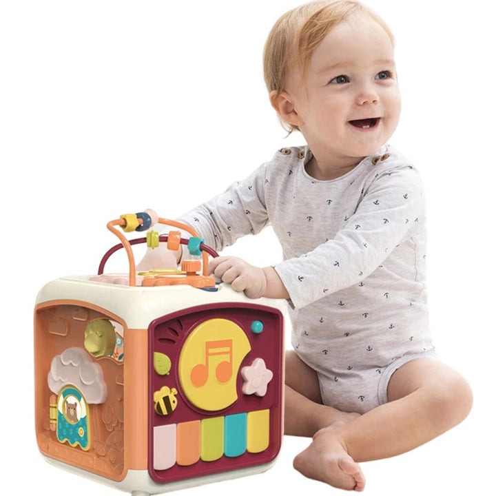 Toddler playing with a colorful baby piano toy that also features a drum.