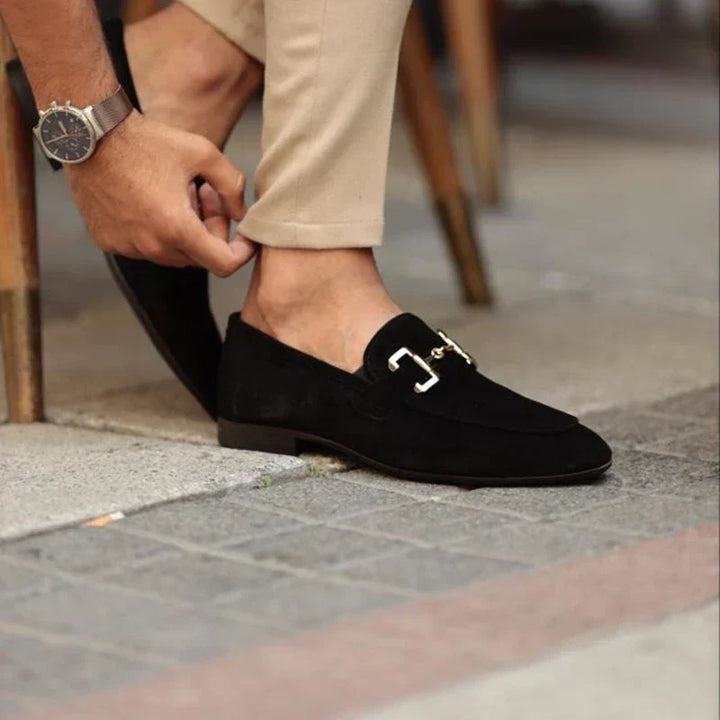 Close-up of a luxurious gold horsebit on stylish black men's slip-on loafers, highlighting premium quality.