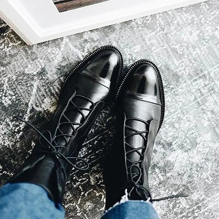 Close-up of black lace-up ankle boots, showing detailed lacing & quality craftsmanship.