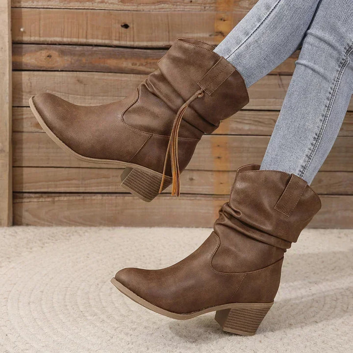 Close-up of elegant women's brown western ankle boots, highlighting the detailed tassel and chic style.