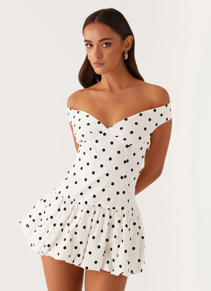 Flattering peplum mini dress with a playful polka dot print and off-shoulder design.