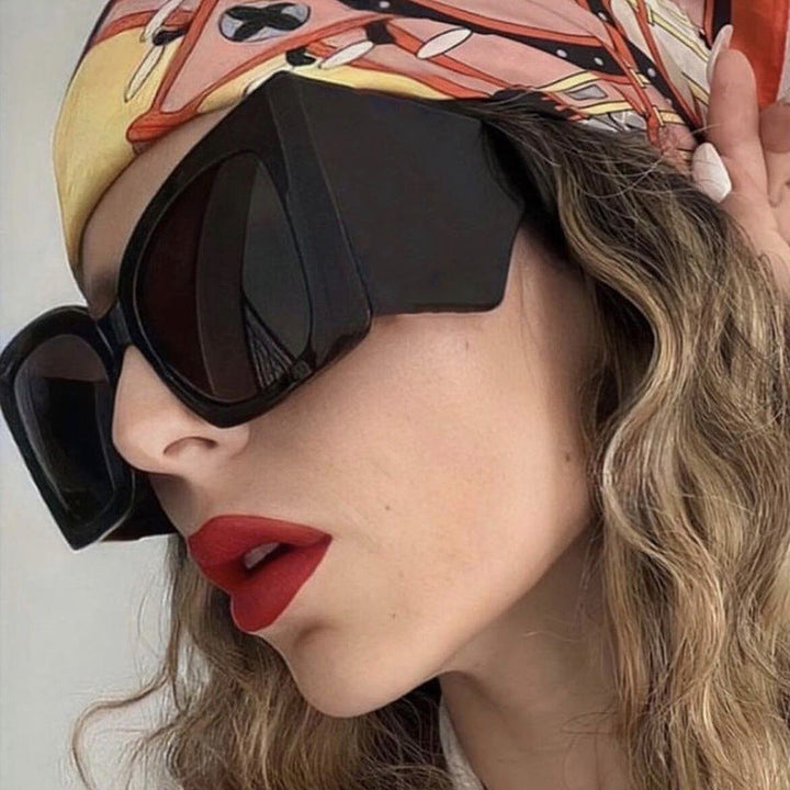 Chic women's oversized cat-eye sunglasses with UV protection. Stylish plastic frame fashion accessory.