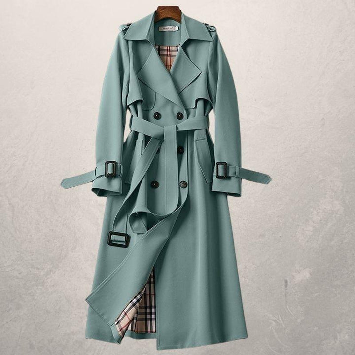 Front view of a women's classic double-breasted trench coat, belted, featuring button details and a wide collar.
