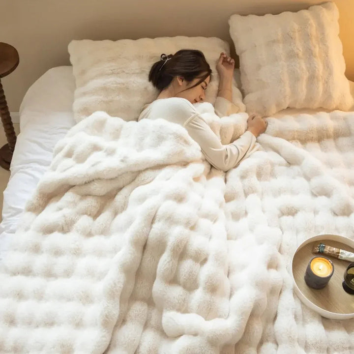 A person snuggled under a warm and cozy plush bubble blanket