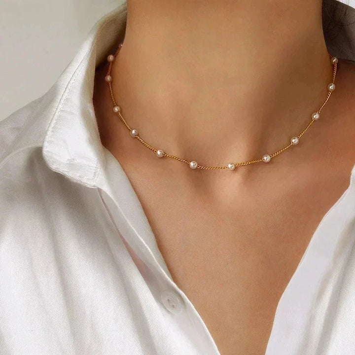Dainty gold-tone choker necklace for women with delicate pearls. Elegant fashion jewelry accessory.