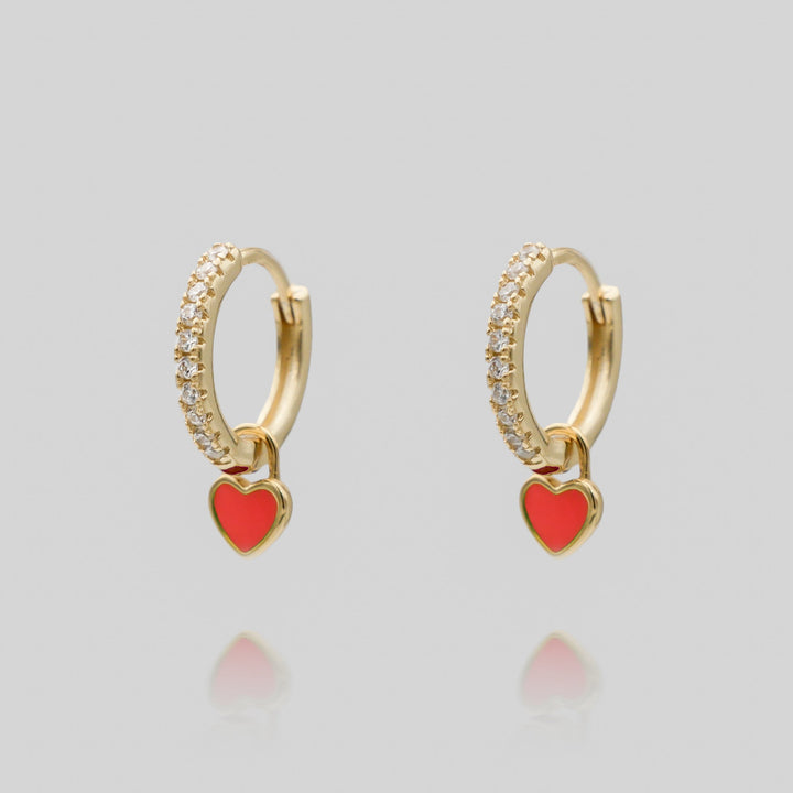 Close-up of a gold plated dainty heart huggie hoop earring, delicate women's jewelry.