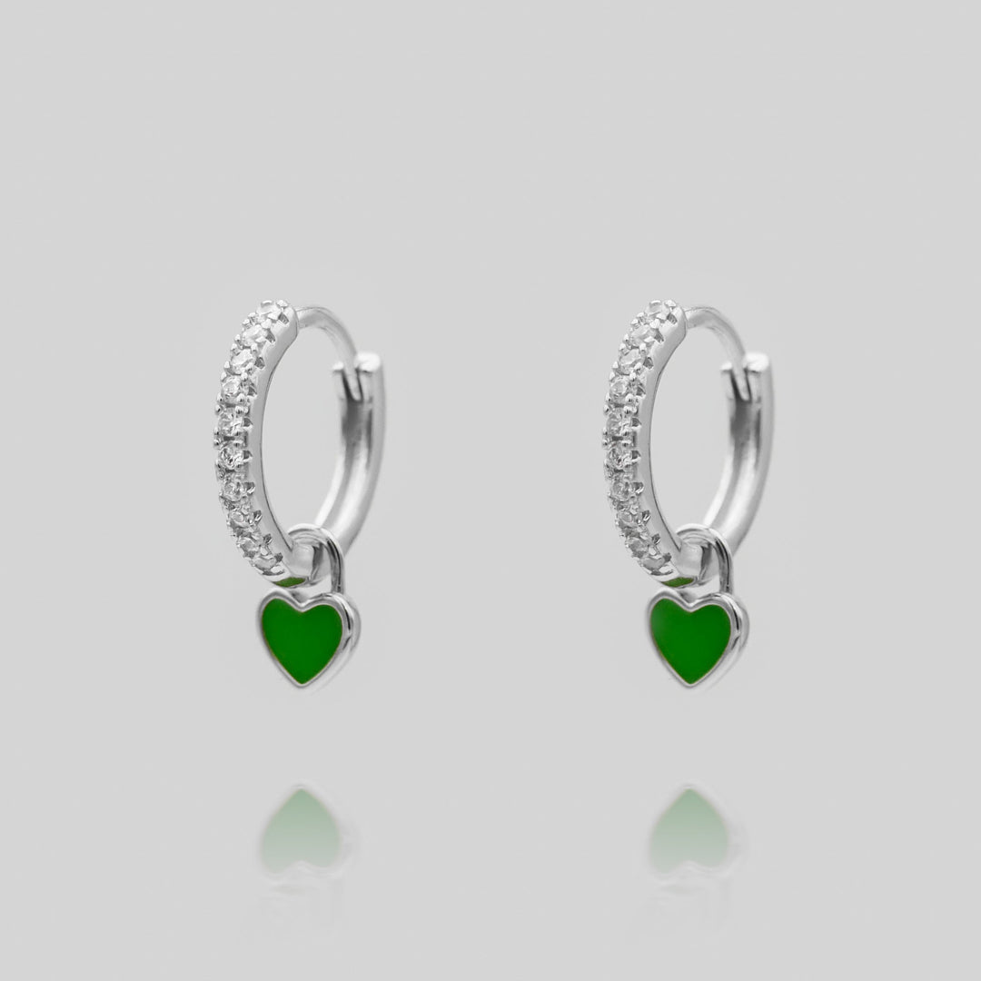 Woman wearing elegant silver plated dainty heart huggie hoop earrings.