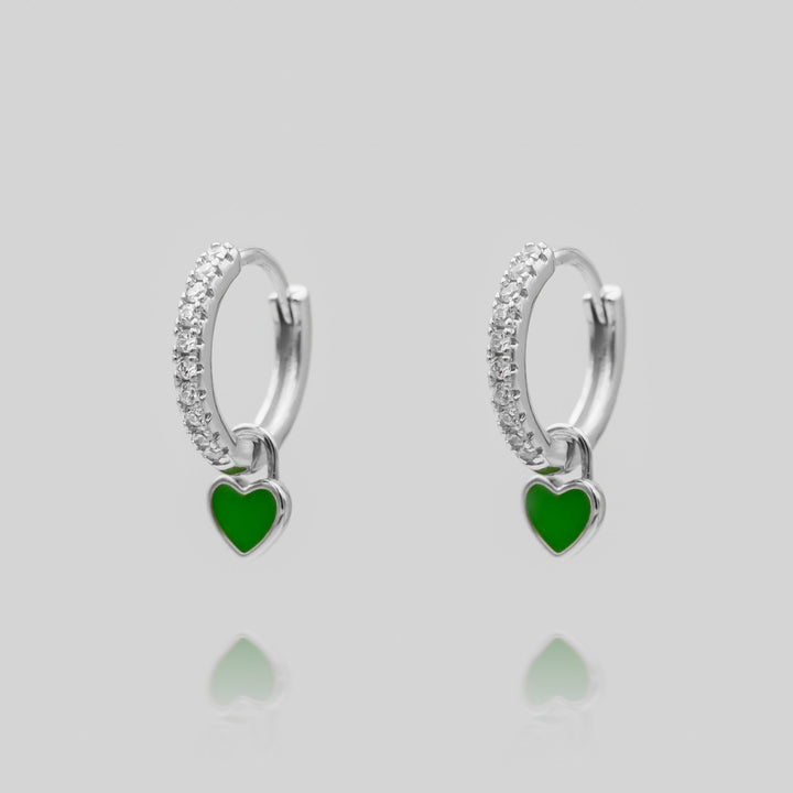 Woman wearing elegant silver plated dainty heart huggie hoop earrings.
