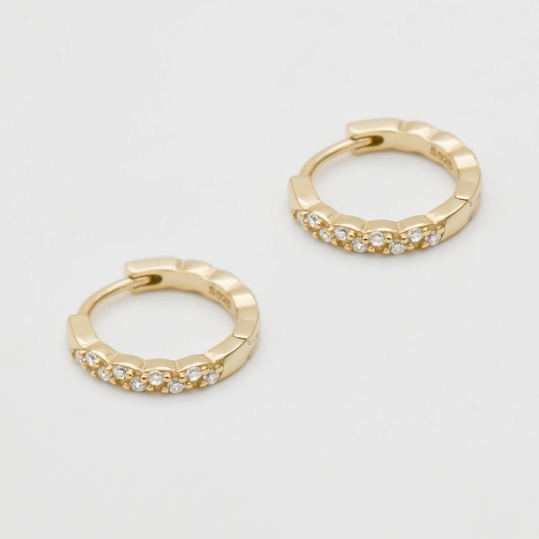 Close-up of elegant gold plated dainty huggie hoop earrings. Versatile women's jewelry for any occasion.