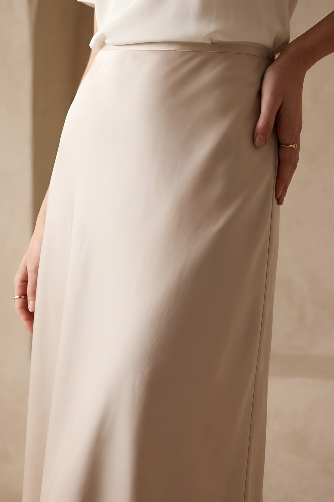 Flowy beige high-waisted A-line midi skirt, offering comfort and elegant style for any woman's wardrobe.