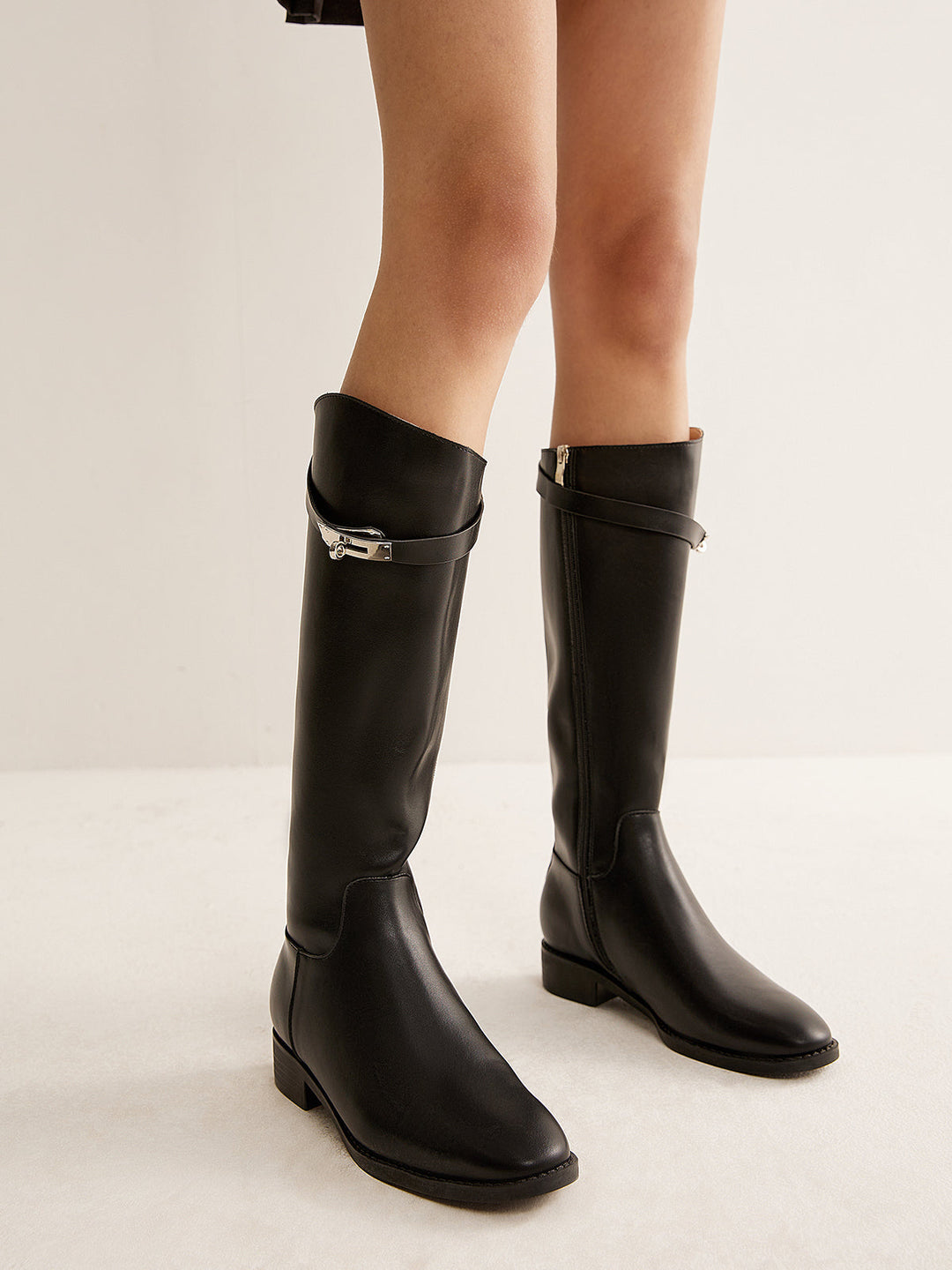 Close-up of elegant black women's knee-high riding boots, showcasing detail for fall/winter fashion.