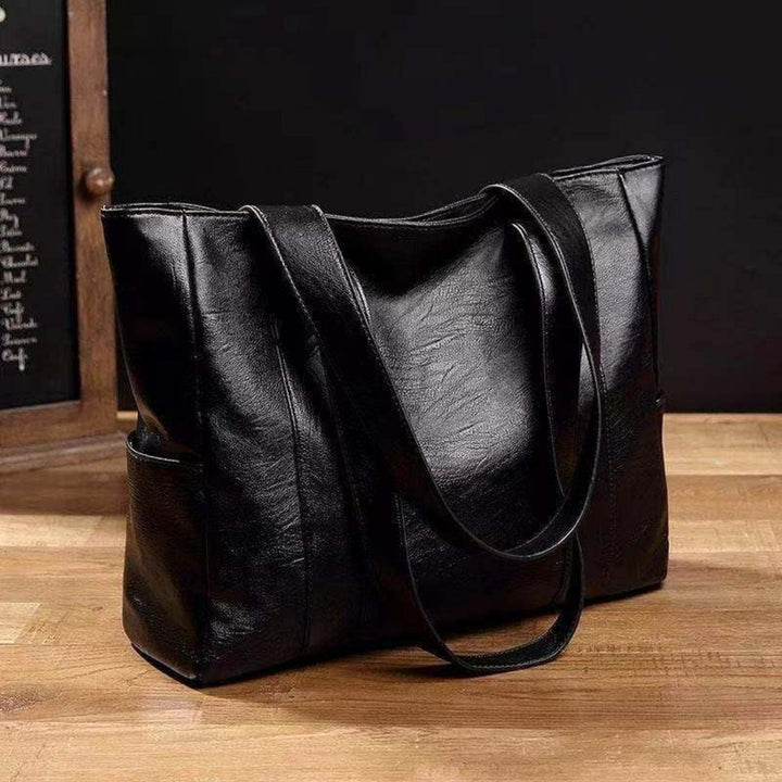 Elegant black women's tote bag with spacious side pockets. Versatile shoulder handbag, ideal for work or travel.