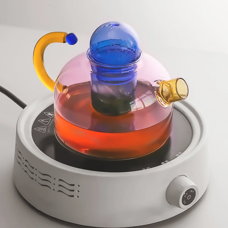 Complete borosilicate glass tea set with colorful tea, enhancing kitchenware & home decor. A thoughtful gift idea.