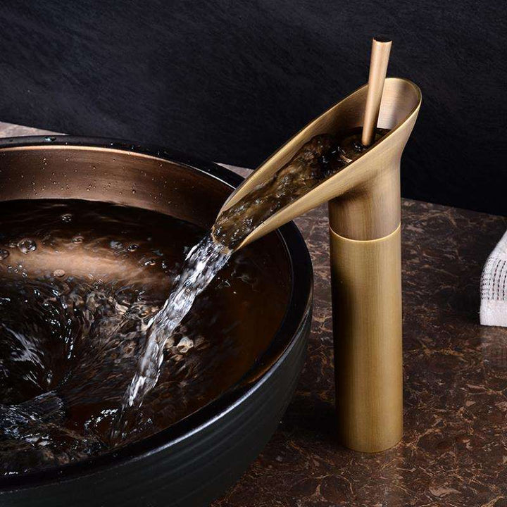 Elegant brass waterfall basin faucet, deck-mounted. Modern bathroom mixer tap.