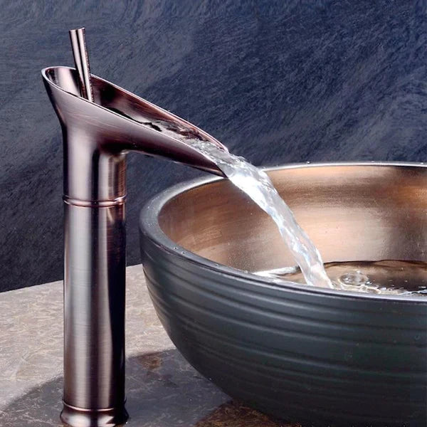 Golden waterfall basin mixer tap, luxury bathroom fixture, deck-mounted.
