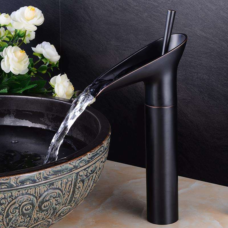 Luxury waterfall sink mixer tap in polished brass finish. Bathroom decor.