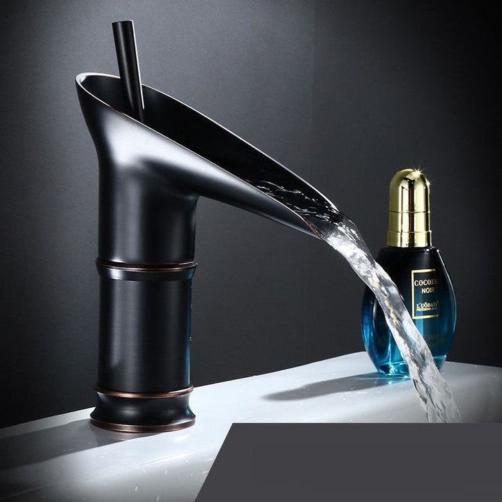 Deck-mounted waterfall basin mixer tap, modern brass finish, luxury fixture.
