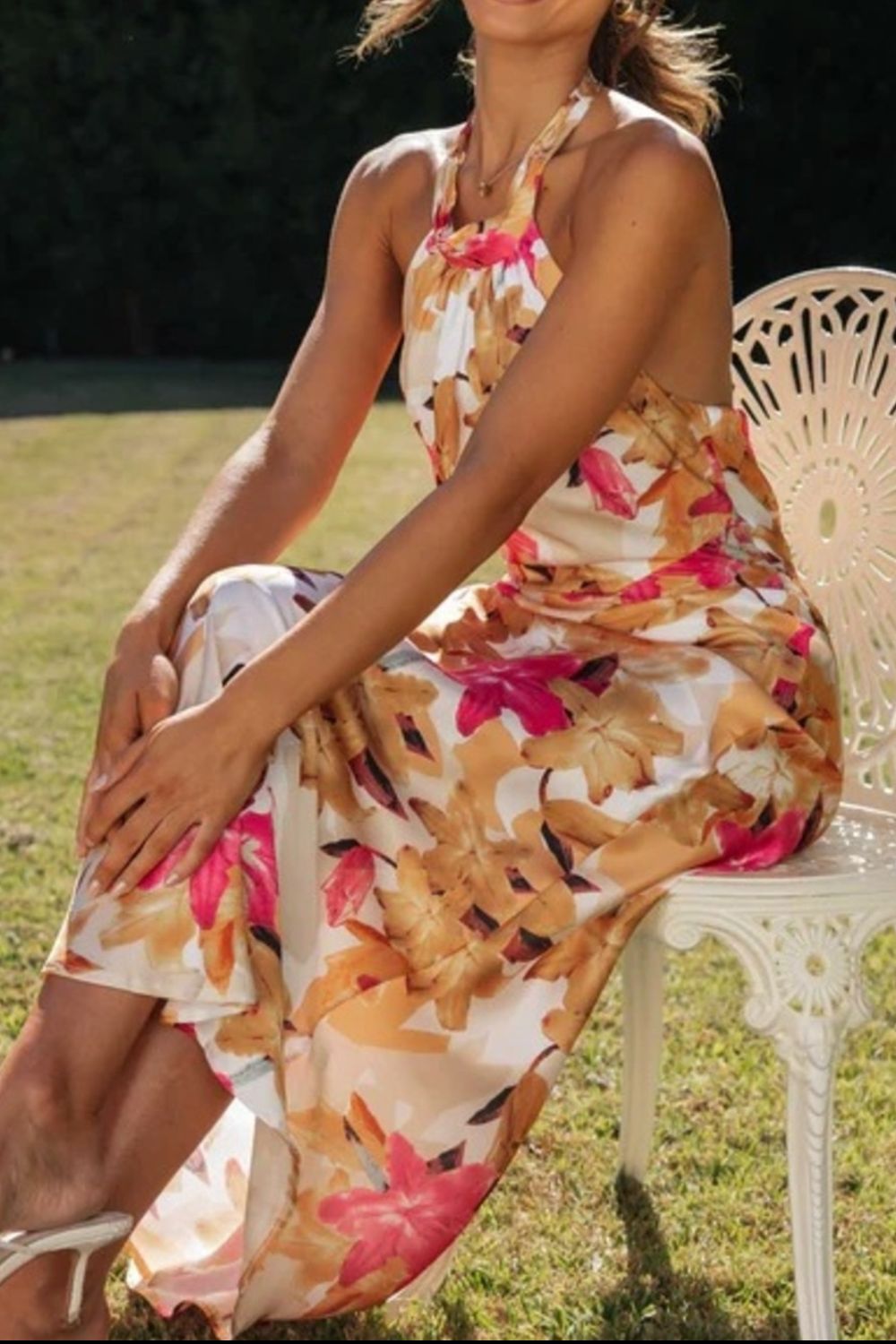 Flowy maxi dress with a vibrant floral pattern and secure halter neckline, suitable for parties.