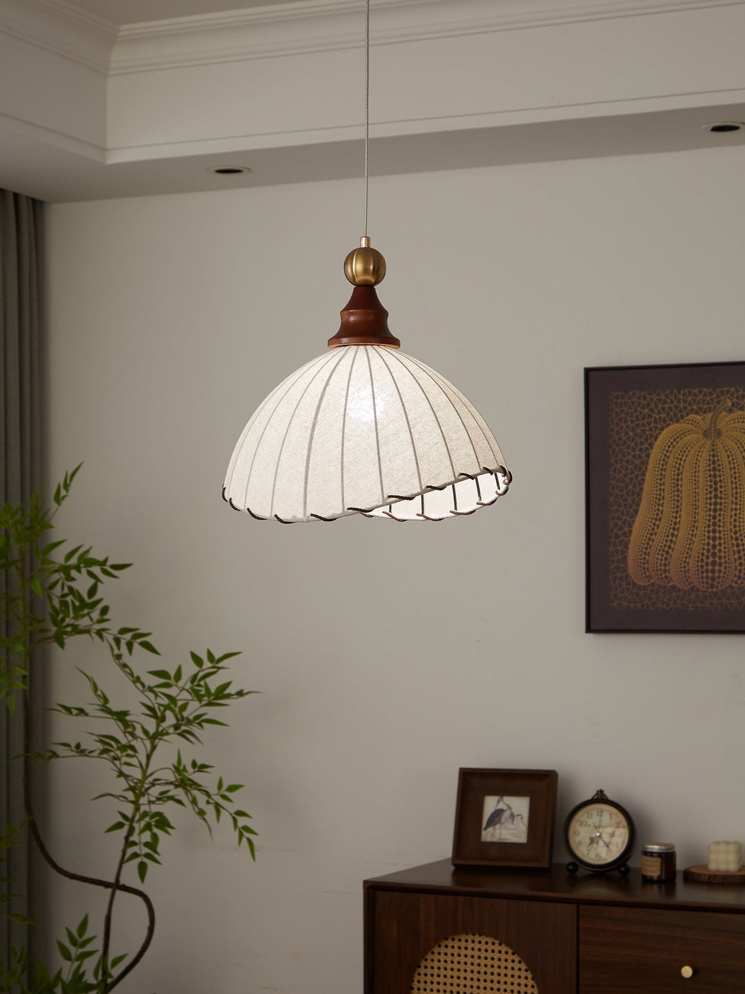 Modern lighting fixture: a sophisticated pendant light with fabric shade and gold & wood details.