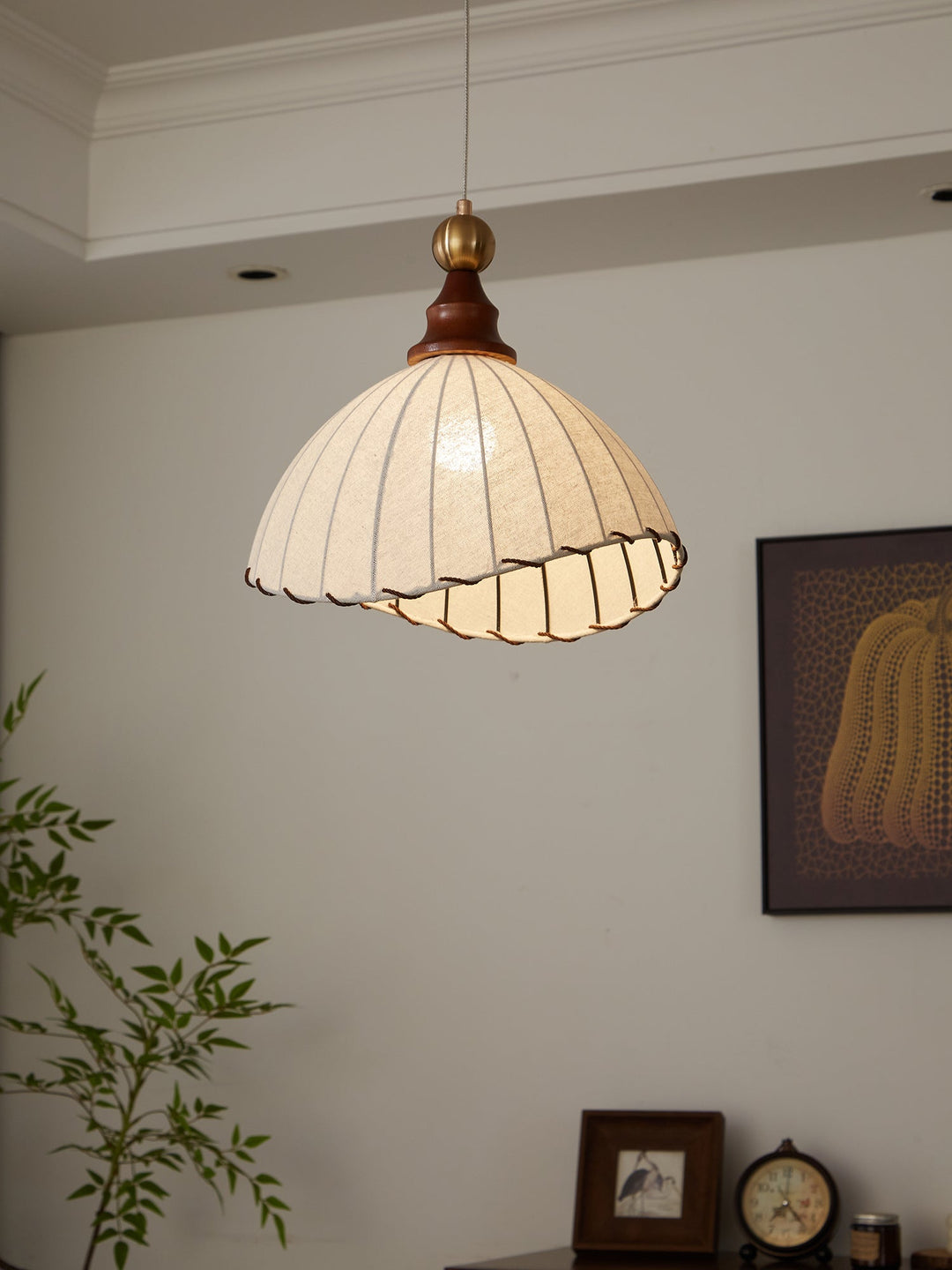 Adjustable pendant light offering a modern, elegant look with fabric, gold, and wood elements.