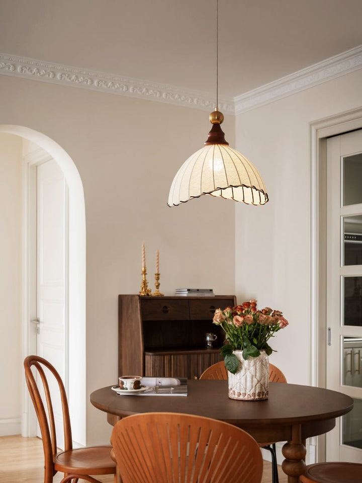 Timeless elegant pendant light with a unique fabric shade, gold finish, and subtle wood accents.