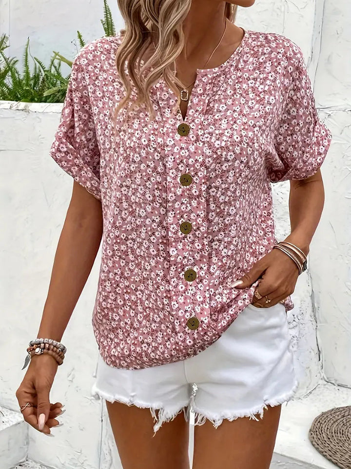 Feminine pink floral blouse with short sleeves and button-down front, great for elegant summer style.