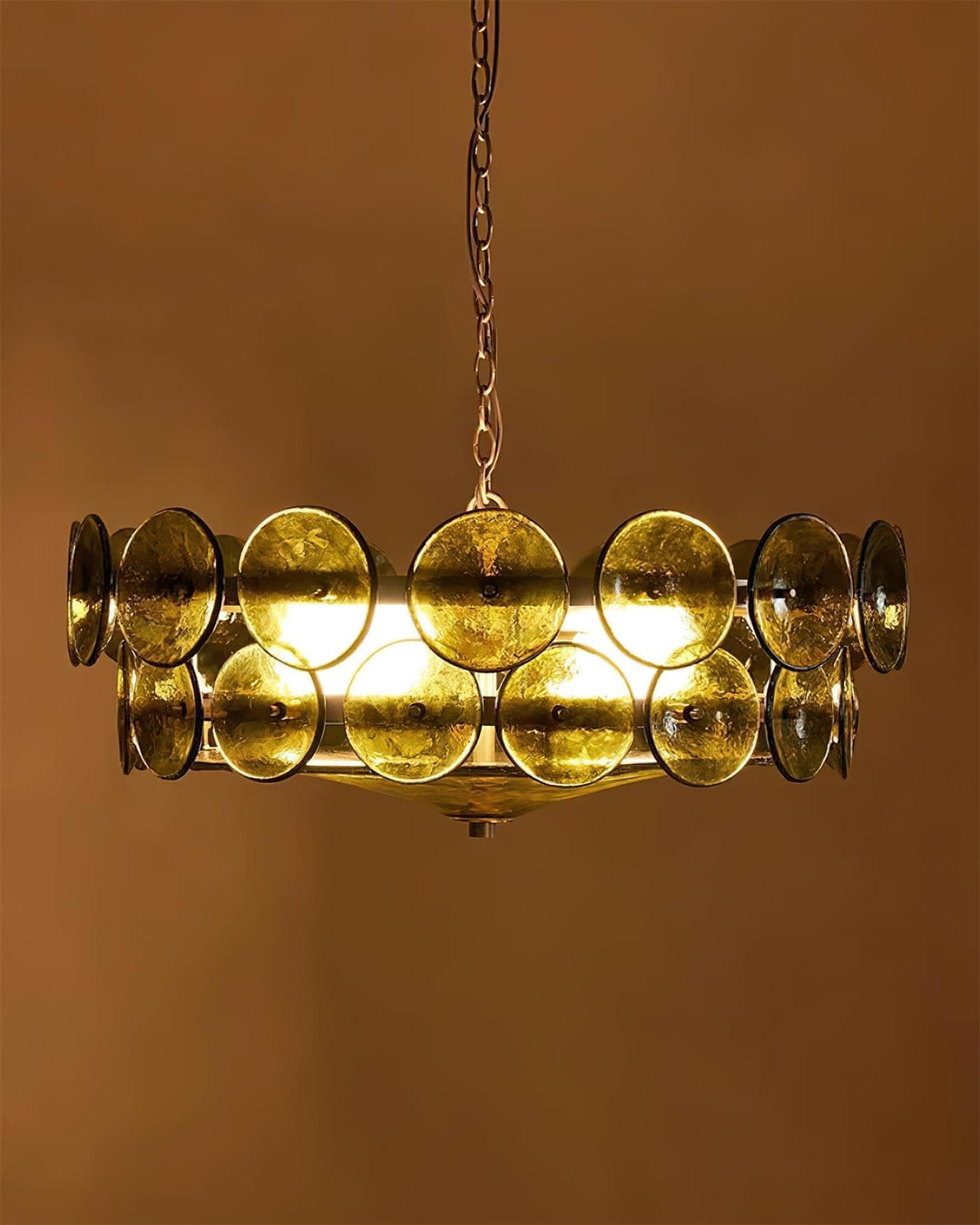Illuminated round glass chandelier casting a warm glow in a contemporary space.