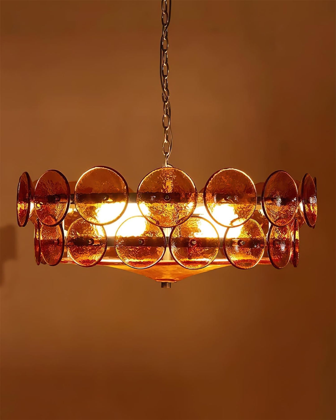 Polished metal frame supporting round glass shades on an elegant chandelier.