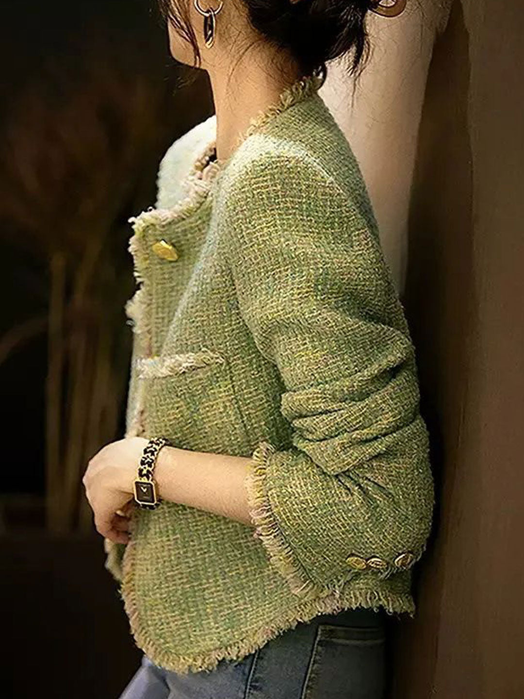 Close-up of a women's black tweed jacket featuring a classic round neckline.