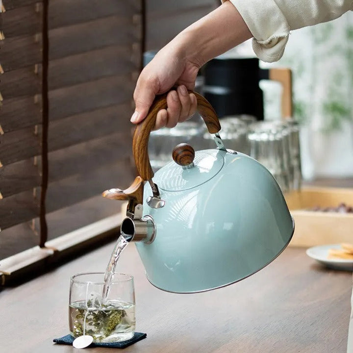Black whistling induction kettle, stainless steel. Features an insulated handle for safe hot water pouring.