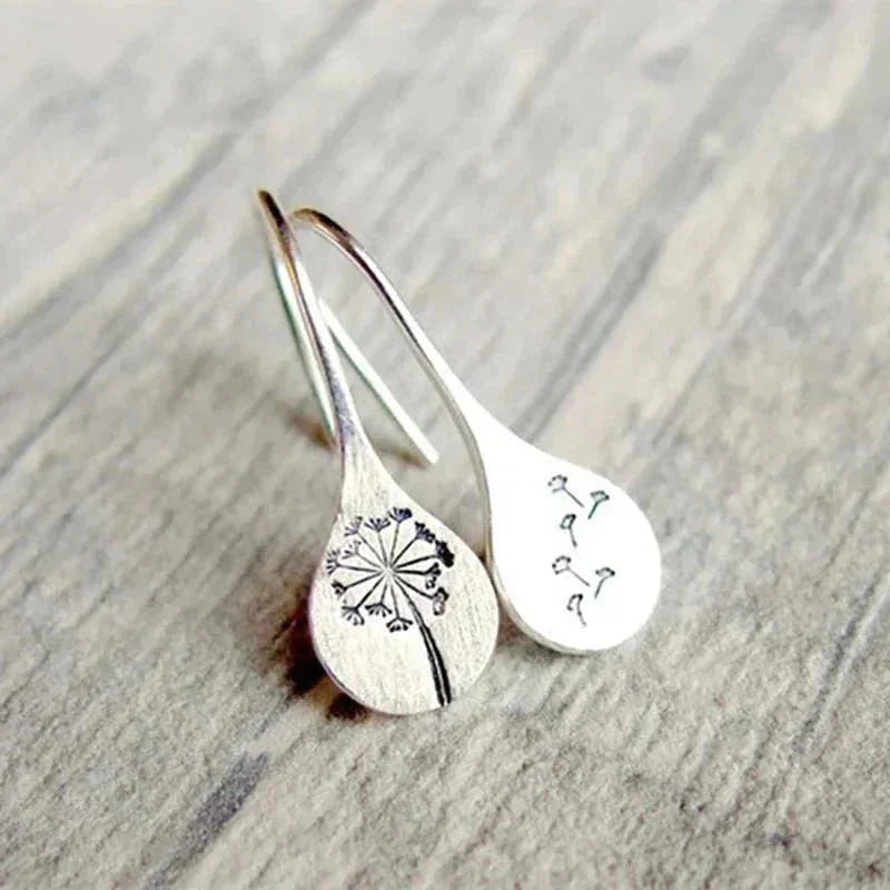 Women's sterling silver dangle earrings with a clear teardrop encasing a real dandelion seed, elegant silver jewelry.
