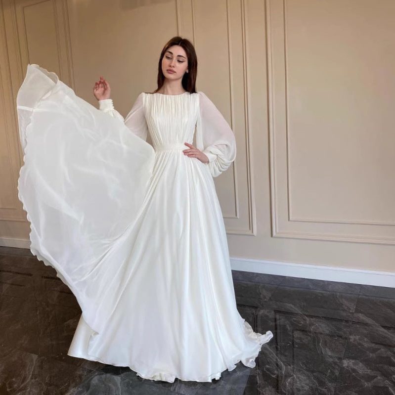 Women's formal white pleated maxi dress with long sleeves. Elegant and flowing, ideal for evening events & wedding guests.