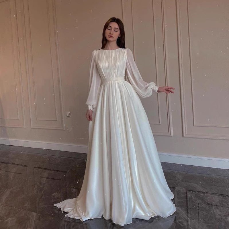 Chic white long sleeve maxi dress for women. Features elegant pleats and a flowing skirt, ideal for formal occasions.