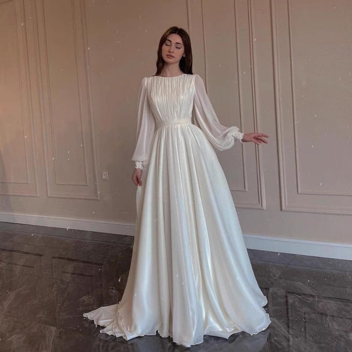 Chic white long sleeve maxi dress for women. Features elegant pleats and a flowing skirt, ideal for formal occasions.