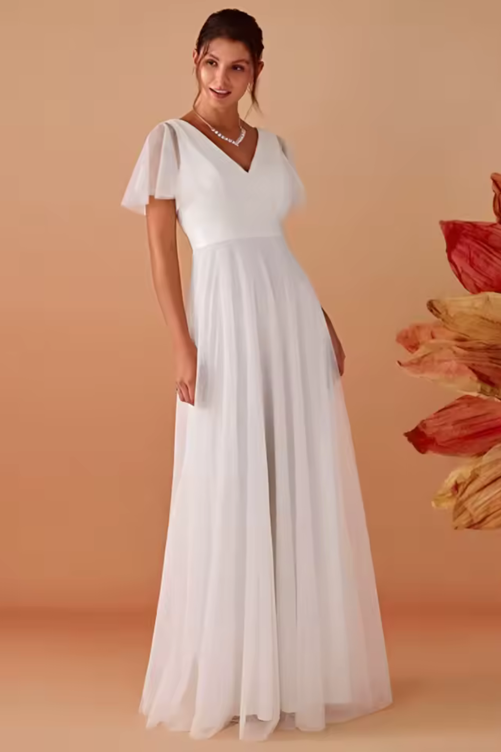 Close-up of the V-neckline and sheer flutter sleeves on a women's elegant white maxi dress, special occasion.