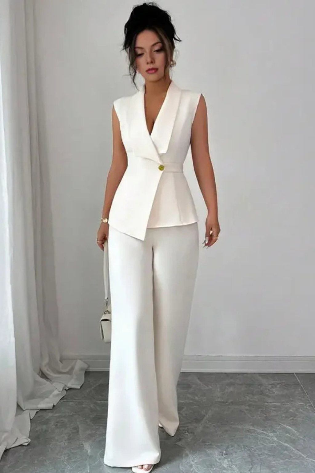 Tailored white two-piece women's suit with sleeveless V-neck blazer and chic wide-leg trousers. Professional look.