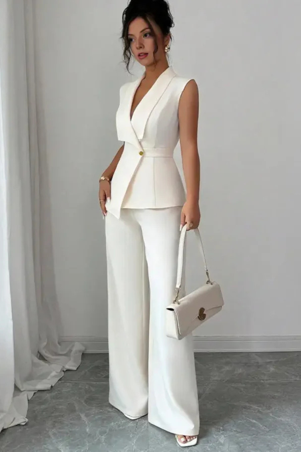 Sleek white women's sleeveless blazer and flowing wide-leg trousers suit set. Modern tailored look.