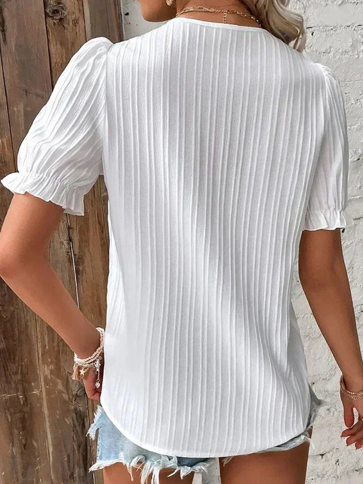 Stylish short sleeve V-neck pleated women's blouse in white with subtle button detail. Available in plus sizes.