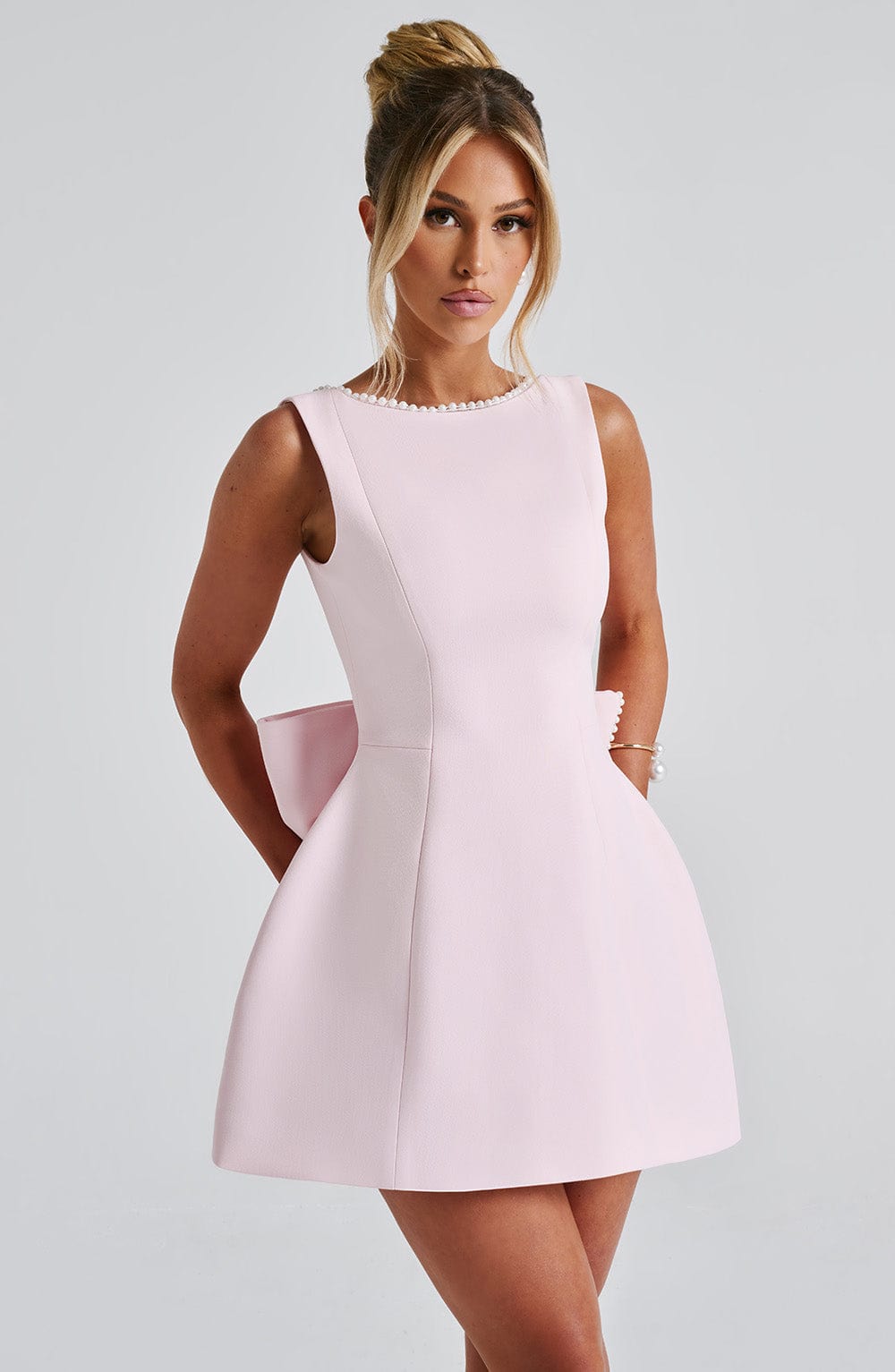 Chic women's bow back A-line mini dress with elegant pearl trim, perfect as a wedding guest or cocktail party outfit.