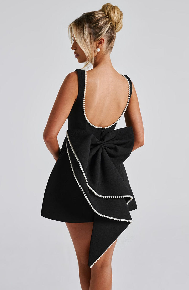 Woman in an elegant pearl trim A-line mini dress, ideal for a wedding guest, cocktail party, or formal event.