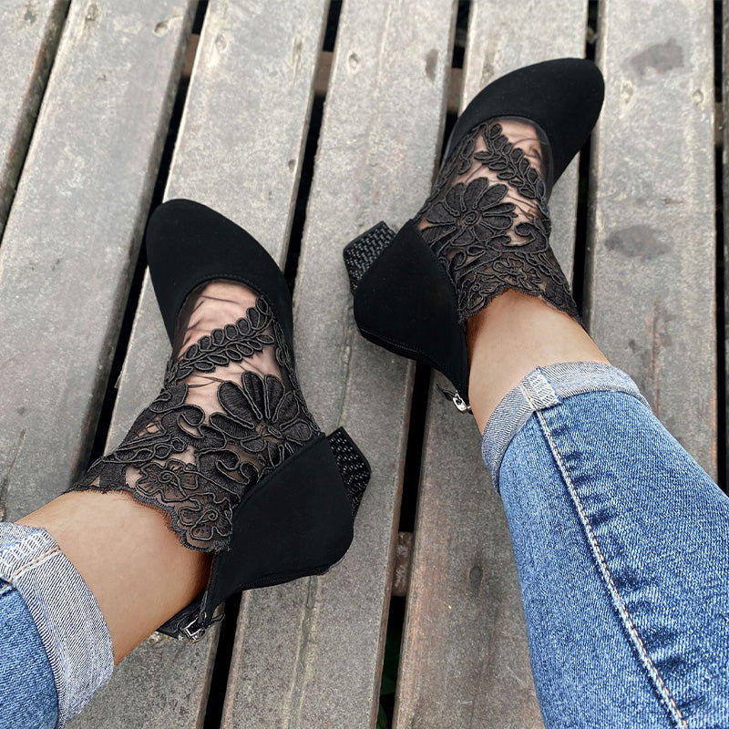 Women's fashion boots: close-up of elegant lace embroidery on black ankle boots with a chic block heel.