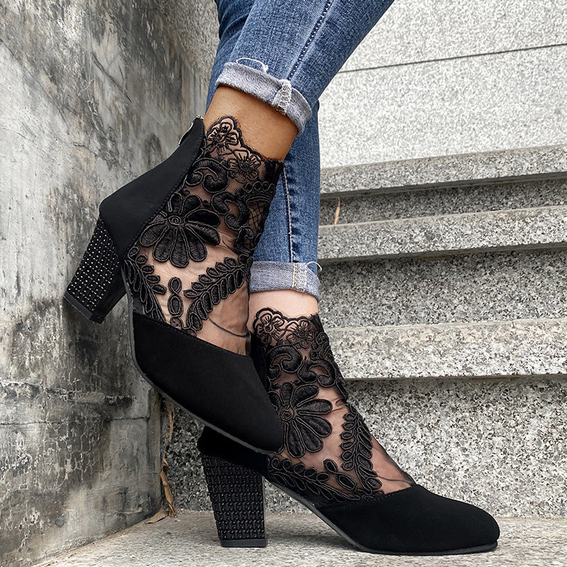 Side view of black women's ankle boots, showcasing delicate lace embroidery & a stable block heel. Fashionable.