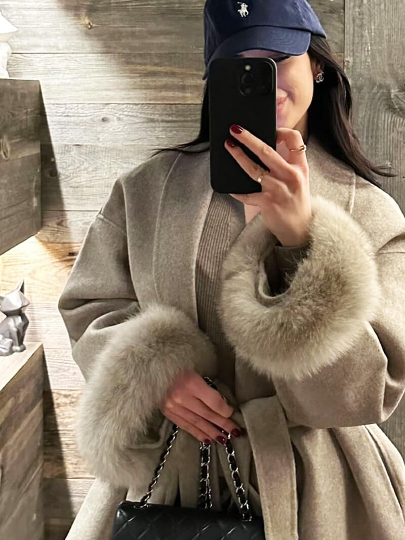 Luxurious women's belted wrap coat for winter fashion, showcasing elegant faux fur cuffs.