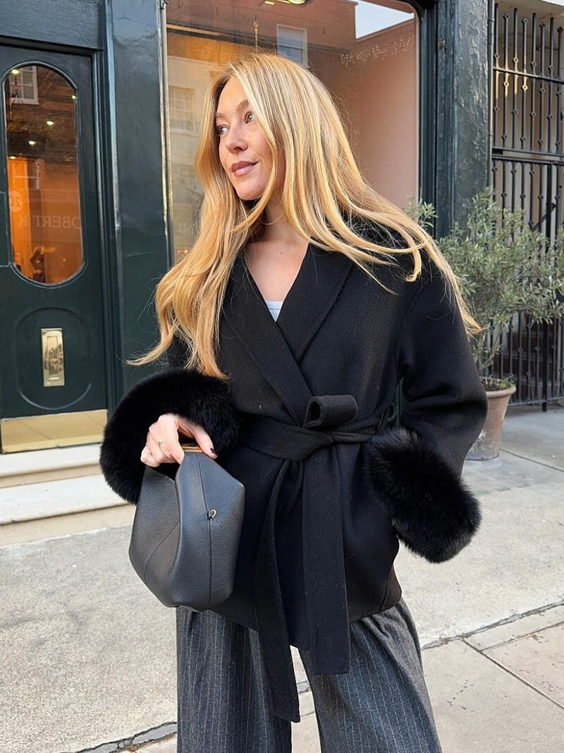 Stylish women's coat with a belted wrap front, shawl collar, and opulent faux fur cuffs.