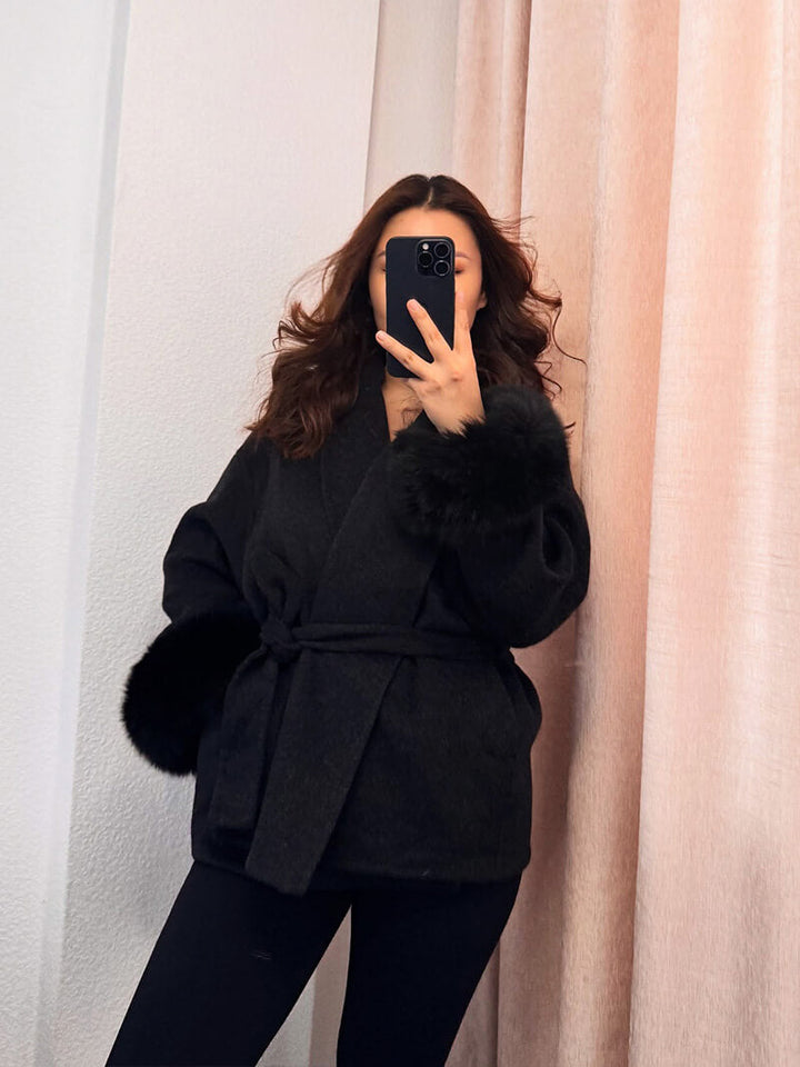 Women's luxury winter coat: belted wrap style, elegant silhouette, and plush faux fur cuffs.