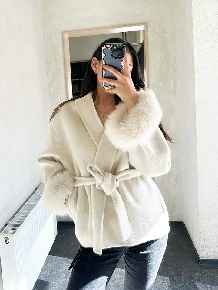 Chic women's fashion coat with a flattering belted wrap silhouette and plush faux fur cuffs.